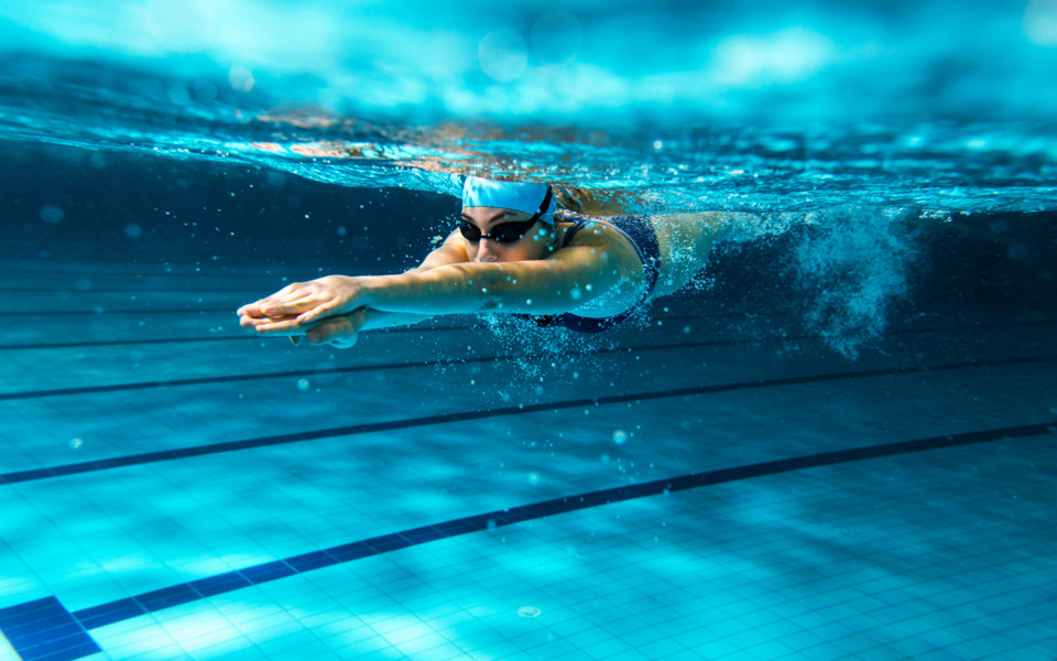 En undervattensbild på en kvinna som simmar under vattnet.